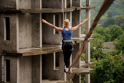 Back view of fearless woman walking on a slackline