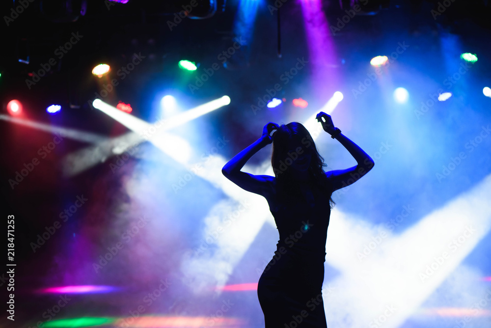 Silhouette of dancing girl against disco lights