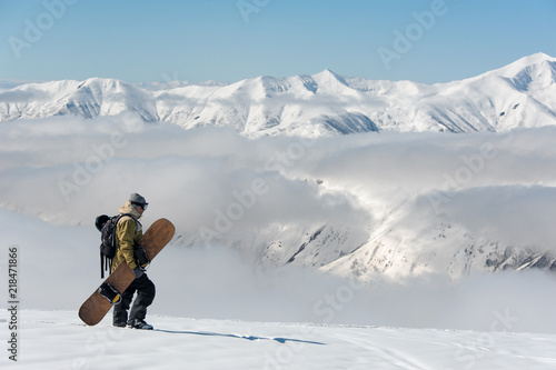 man in warm ski equipment slowly wanders against the background of snowy mountains