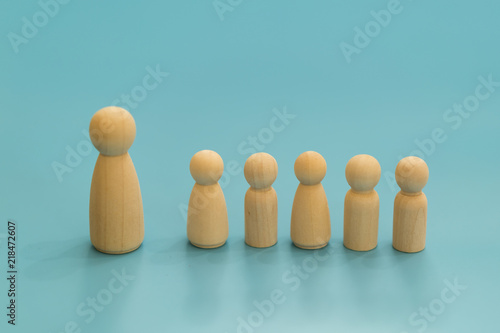 concept lonely dad with children. Wooden figurines of dad and children on a blue background. The concept of a large father.