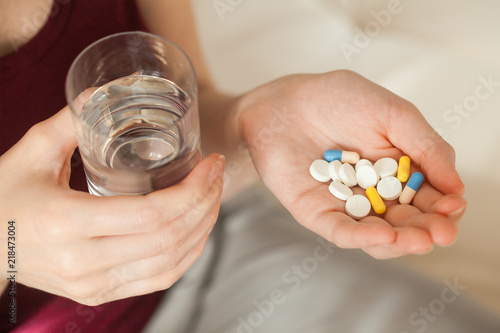 young woman holding pill and glass of water