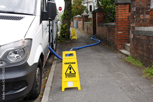 Mobile house cleaning van with caution signs and water pipe