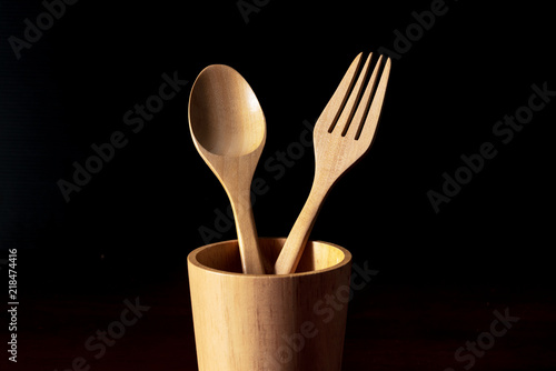 spoon and fork kitchen utensils in wooden cup low key background