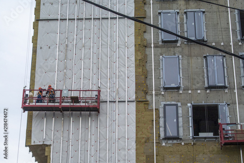 Construction of a hotel. Workers on suspended scaffolding 