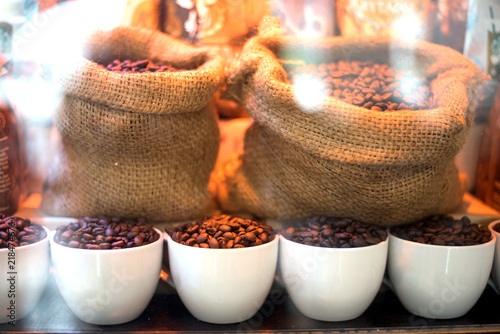 Coffee beans in white cups and sacks behind the glass in showcases for decoration in coffee shop or cafe looking feel fresh and good smell.
