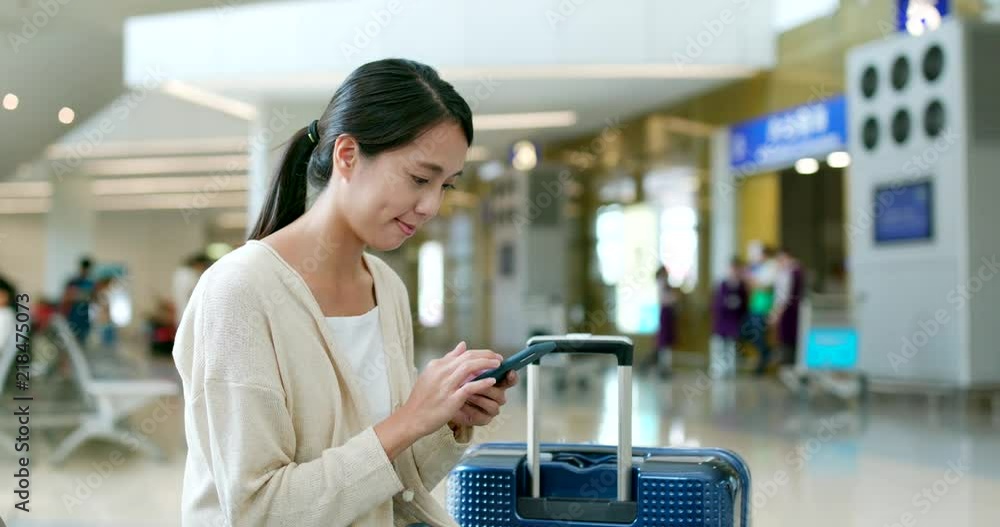 Woman checking flight number on mobile phone in the airport Woman checking flight number on mobile phone in the airport