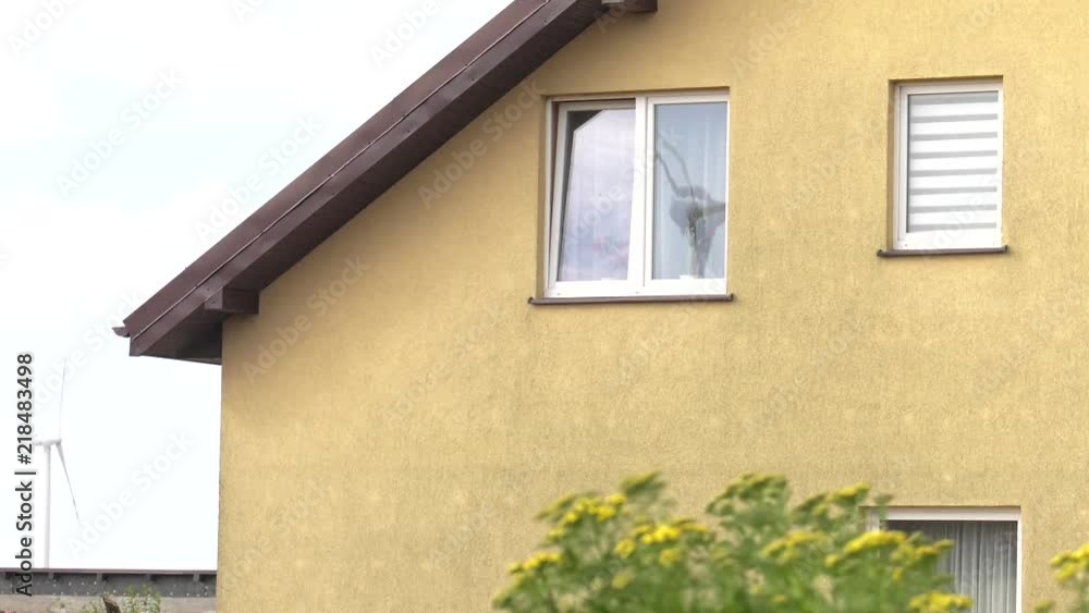 The windmill from the wind farm is spinning. It bounces off the window of the house. Single-family house in the background. The windmill from the wind farm is spinning. It bounces off the window of the house. Single-family house in the background.