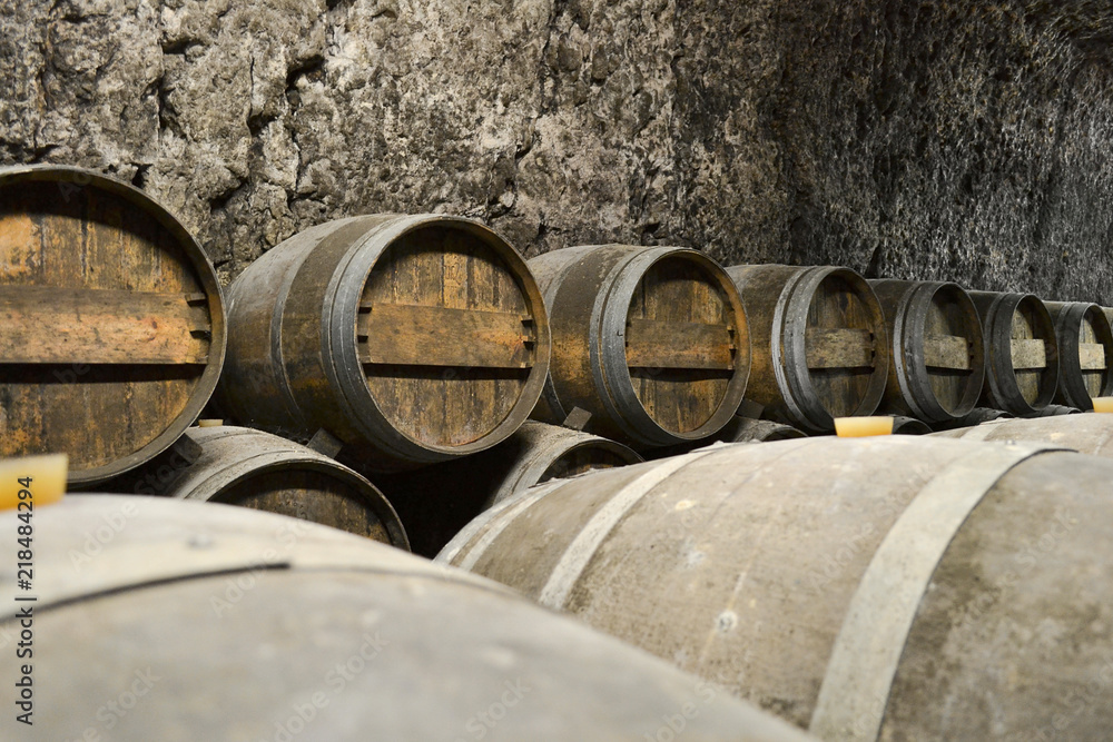 Old wooden barrels with wine in a wine vault, aged traditional wooden barrels up in cool and dark cellar, Old wooden barrels with wine in a wine vault, aged traditional wooden barrels up in cool and dark cellar,