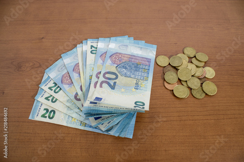 Many 20 euro banknotes and coins on a wood table