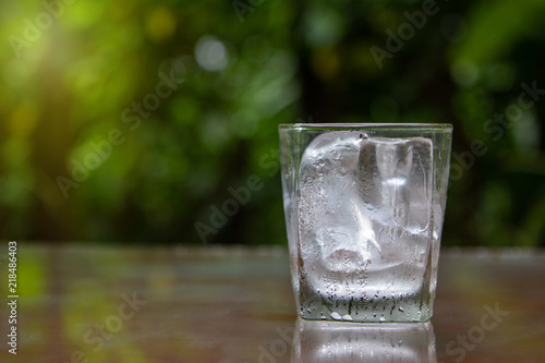 Glass with ice Put on wooden floor Green background of nature