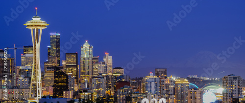 Panoramic beautiful Seattle illuminated skylines downtown during blue hour, view from Kerry Park at Queen Anne Hill. Mount Rainer can be seen from background.