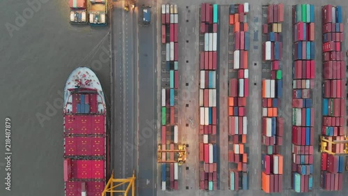 Aerial view over industrial import or export port of Thailand in Bangkok with many rows and stacks of container and big container loader ship vessel.