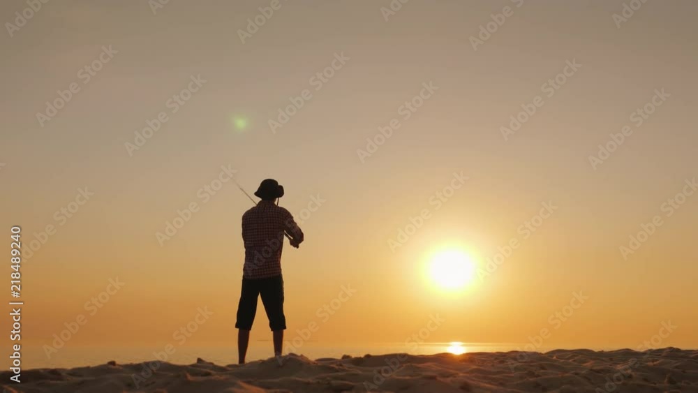 Silhouette of the fisherman, casting spoon-bait into the lake Silhouette of the fisherman, casting spoon-bait into the lake