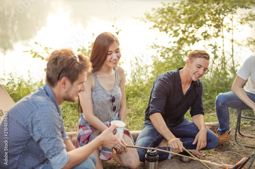 young pretty woman is holding a stick and looking at the campfire. close up photo photo