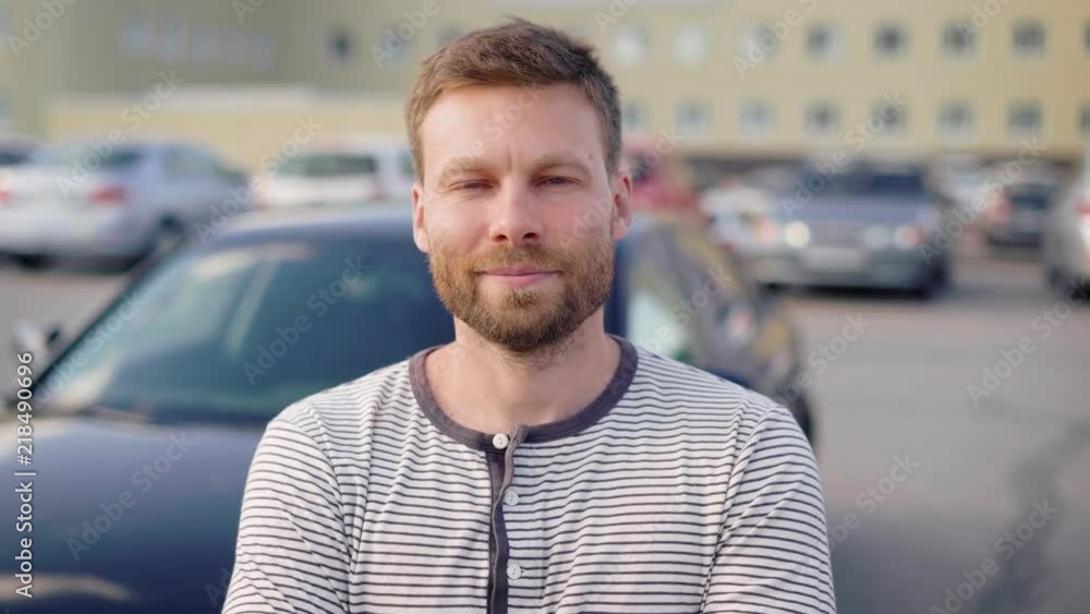 Portrait of a successful man standing by his car on the outside parking lot and smiling. Portrait of a successful man standing by his car on the outside parking lot and smiling.