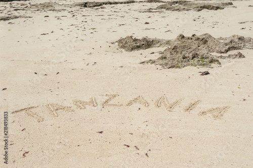 Inscription Zanzibar, Tanzania on the light sand on the beach at low tide