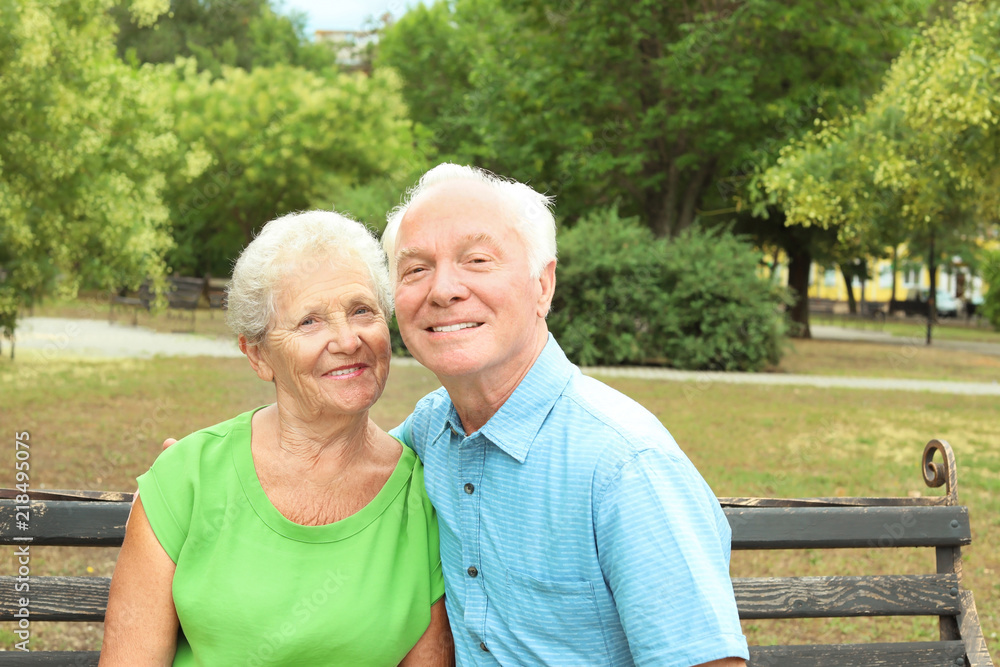 Elderly couple resting on bench in park Elderly couple resting on bench in park
