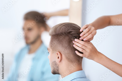 Professional hairdresser working with young man in barbershop. Trendy hair color