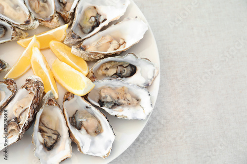 Fresh oysters with cut juicy lemon and space for text on table, top view