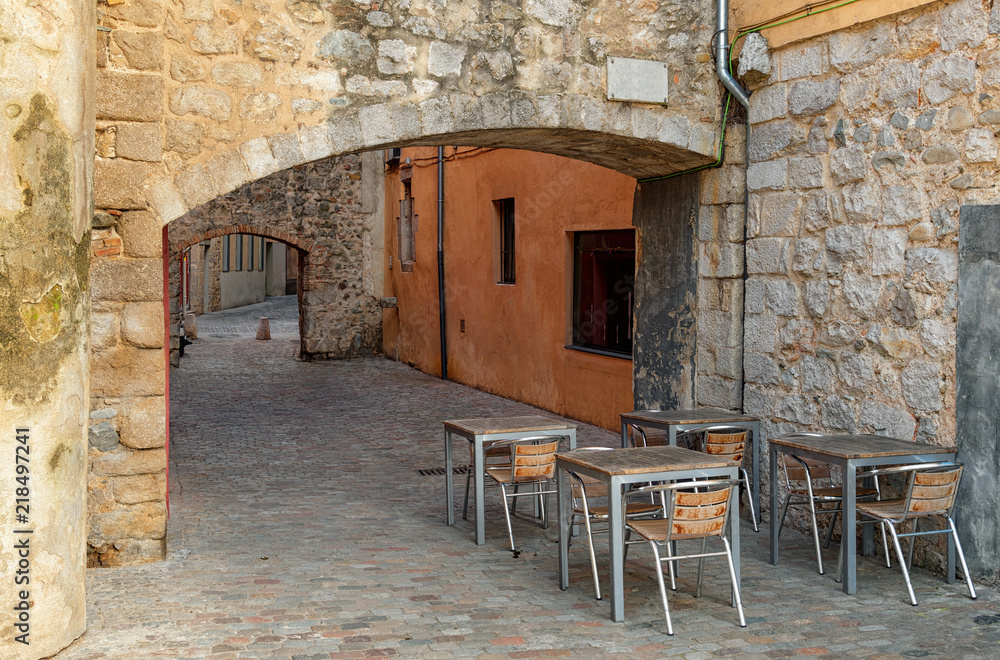 Empty outdoor cafe in the medieval street in Girona Spain