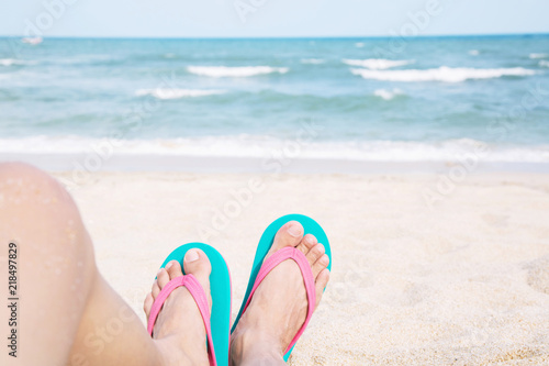 Young people wear the shoes sandals closeup feet sleeping relaxing on beach on sand enjoying chill sun on sunny summer day. Enjoying the sea / ocean. Focus is on the feet. travel vacation holidays.