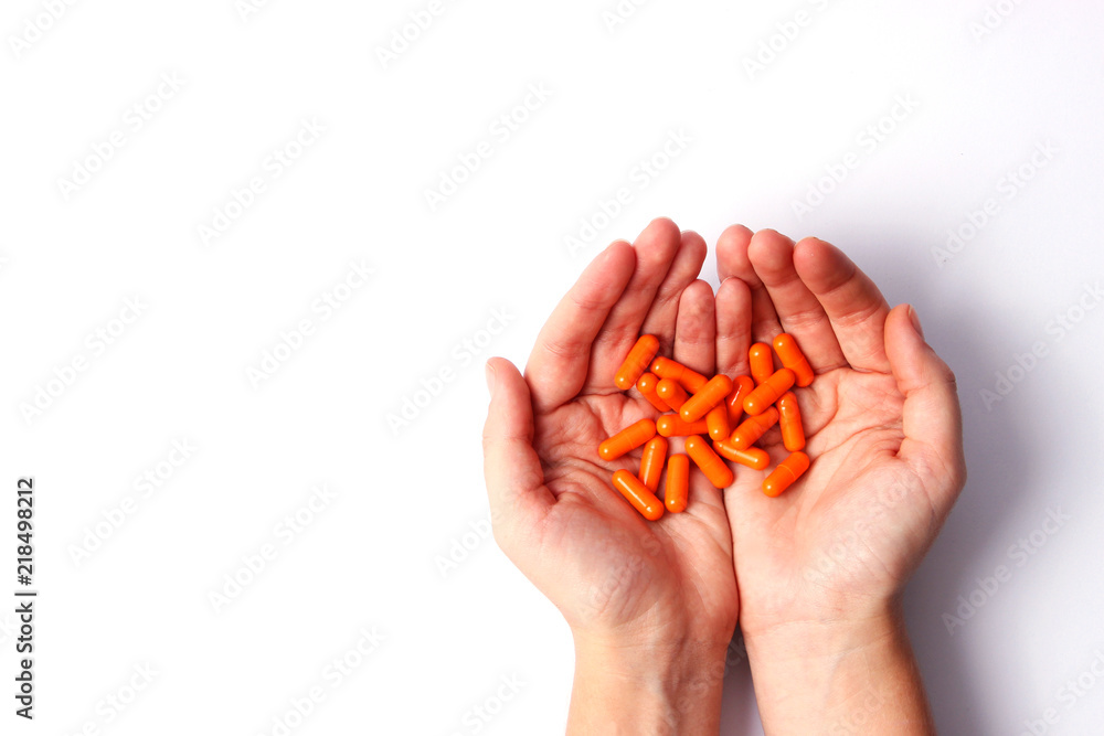 Orange pills in a female hands with a place for the text on a white background. Medecin, health. Orange pills in a female hands with a place for the text on a white background. Medecin, health.