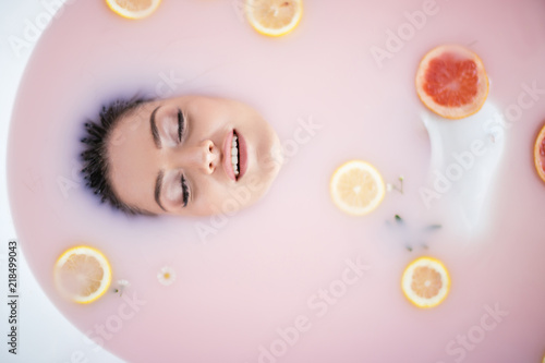 Beautiful girl in milk bath, selective focus on face. Spa and skin care concept. Healthy Face and hands, rejuvenation. photo