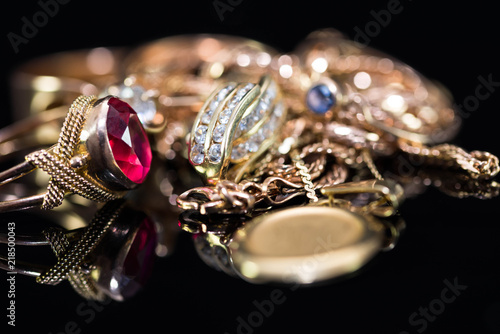 Real gold rings with diamonds, gem, neckless close up macro shot on black background.
