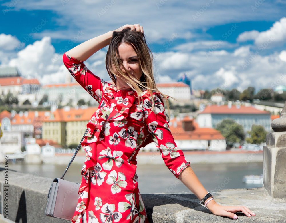 Beautiful girl in red dress travel in Prague, city streets