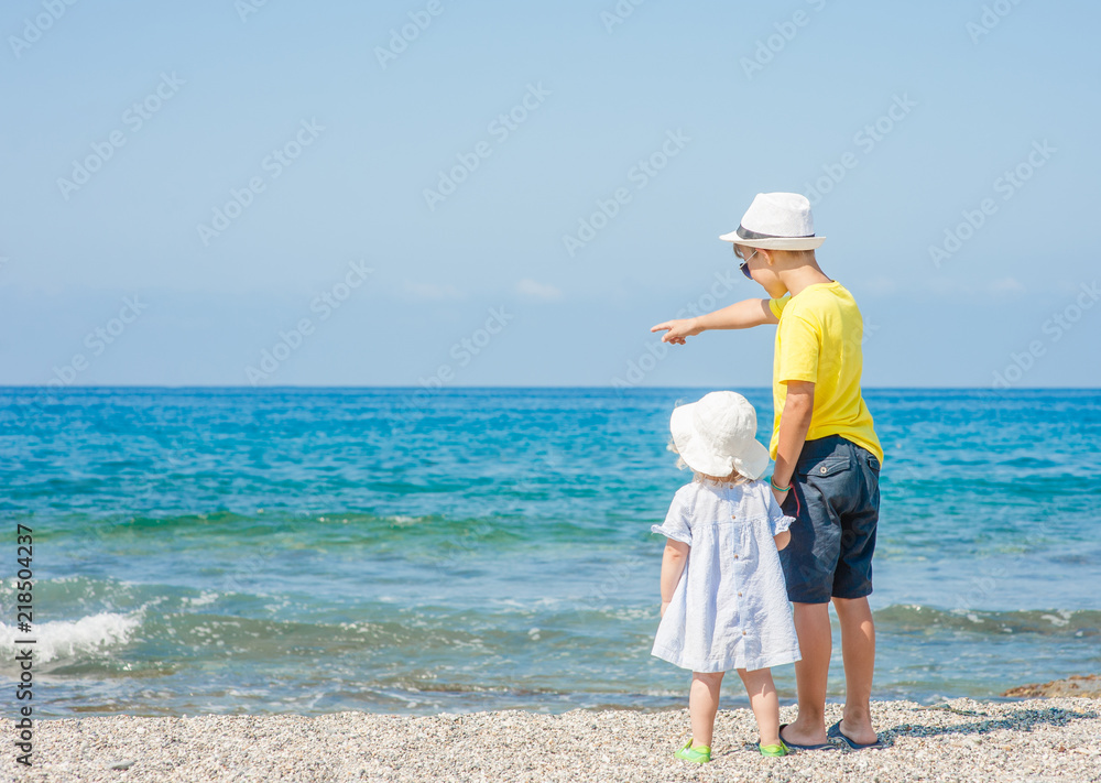 Boy and baby girl on the beach on summer holidays. concept of summer family vacation. Space for text Boy and baby girl on the beach on summer holidays. concept of summer family vacation. Space for text
