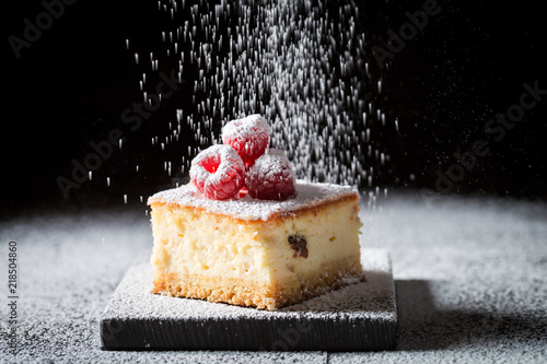 Falling powdered sugar on cheesecake with raspberries