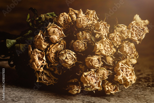 withered bouquet of rose flowers in vintage tone with sun flare