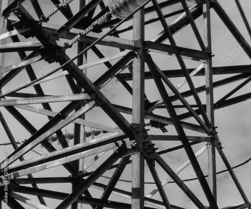 Fragment of high-voltage tower. Power line. Metalware. Black and white photo. BNW. Urban grunge