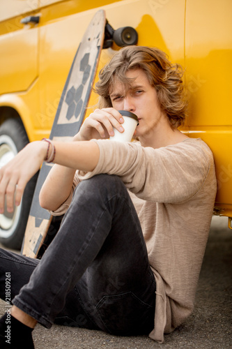 young man sitting in urban city park drinking coffee and relaxing photo