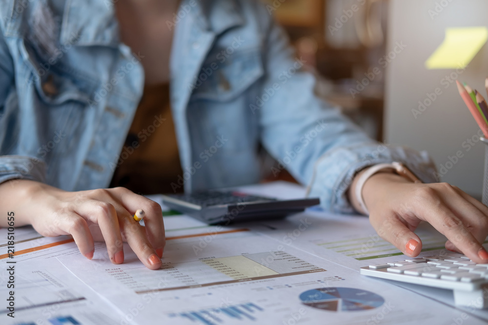 Fototapeta premium Woman using calculator while working for financial documents