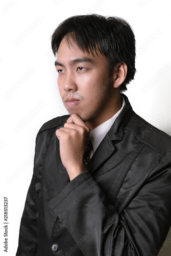 Handsome young man in full suit adjusting his necktie and looking at camera while standing against white background. Handsome young man in full suit adjusting his necktie and looking at camera while standing against white background.