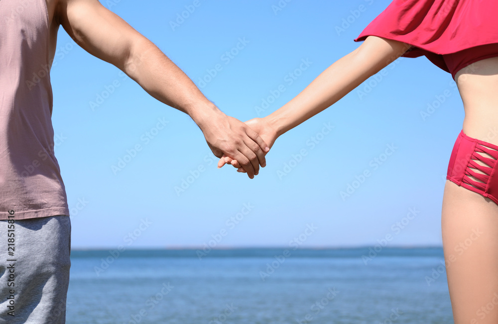 Happy couple holding hands at beach on sunny day, closeup Happy couple holding hands at beach on sunny day, closeup