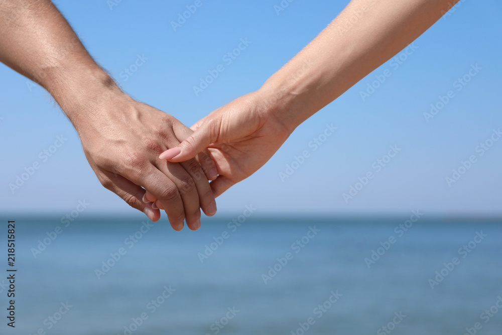 Happy couple holding hands at beach on sunny day, closeup Happy couple holding hands at beach on sunny day, closeup