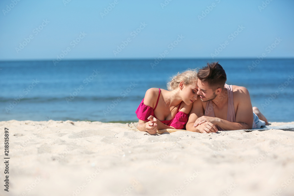 Happy young couple lying together at beach on sunny day Happy young couple lying together at beach on sunny day