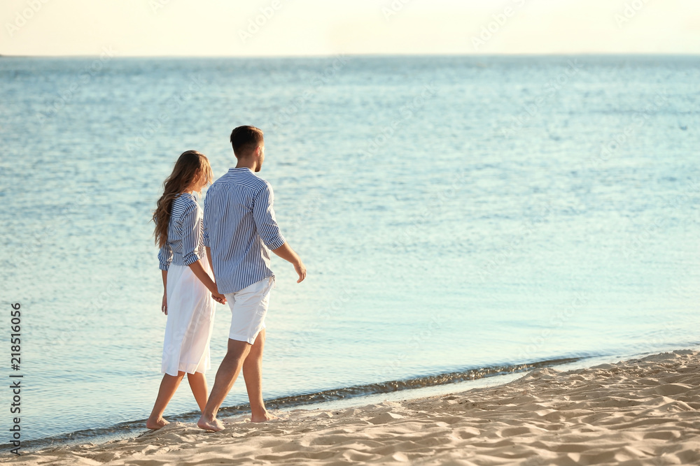 Happy young couple walking together on beach Happy young couple walking together on beach