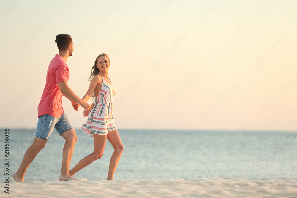 Happy young couple running together on beach Happy young couple running together on beach