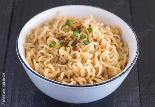Plain noodles in small bowl close up on rustic black table