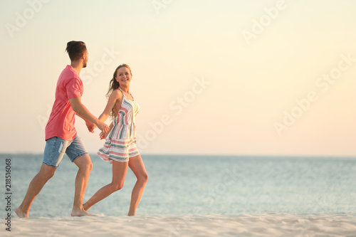 Happy young couple running together on beach