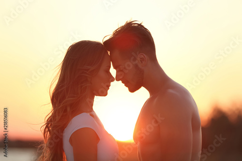 Happy young couple in beachwear outdoors at sunset
