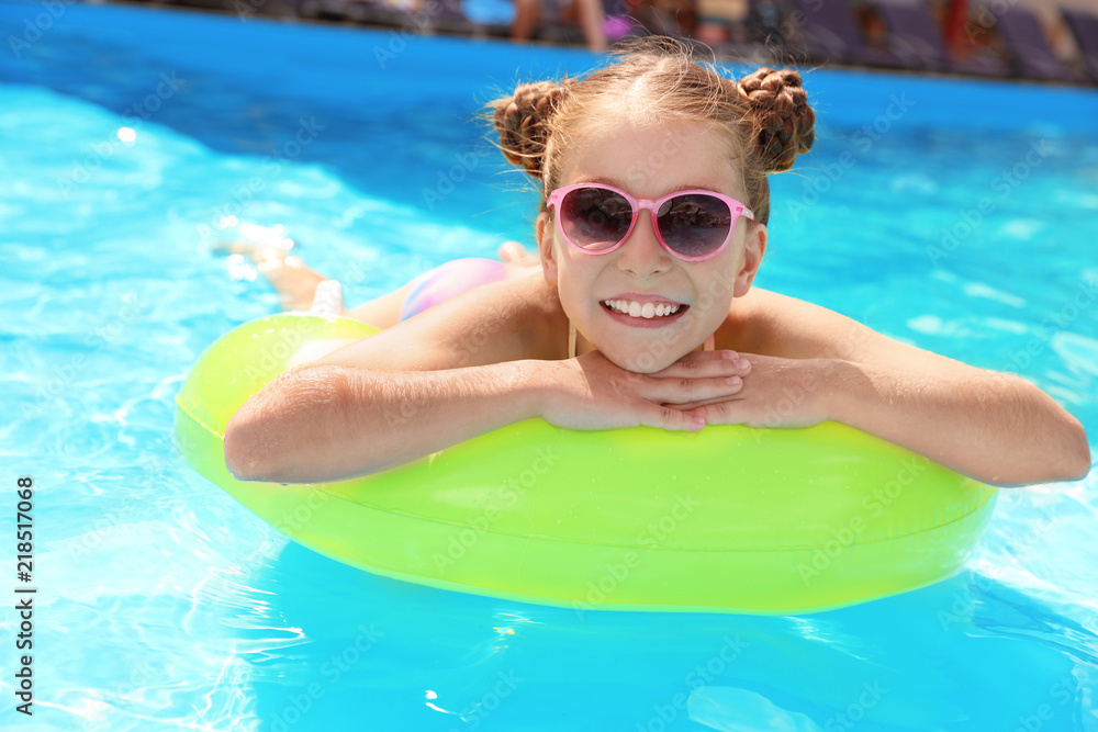 Little girl with inflatable ring in swimming pool
