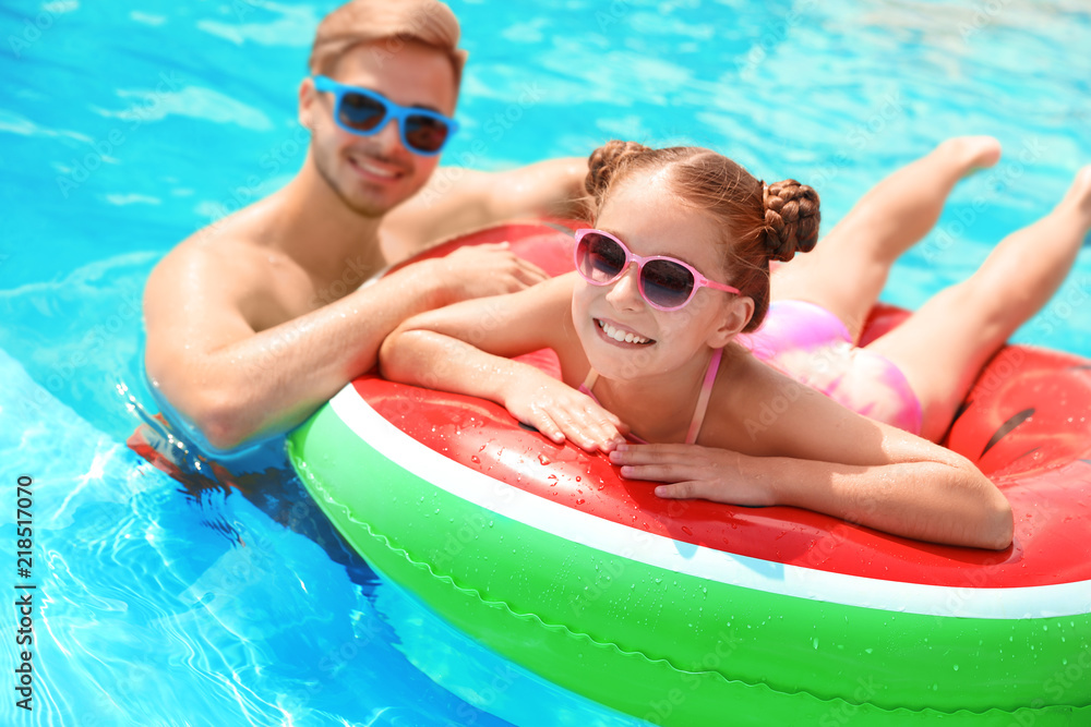 Young man with daughter in pool on sunny day