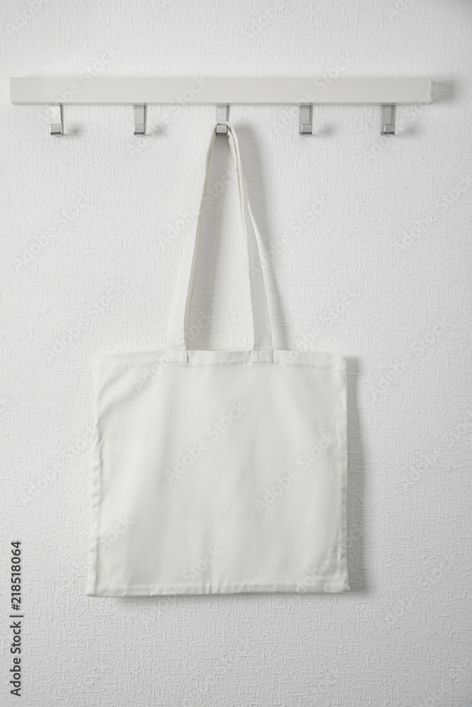 Tote bag hanging on white wall. Mock up for design Tote bag hanging on white wall. Mock up for design