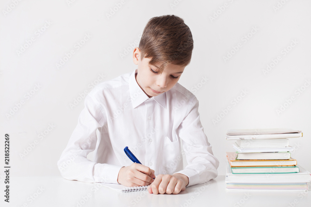School boy writes in notebook at the table School boy writes in notebook at the table