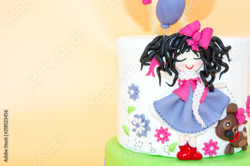 A Cake With a Dolly with Long Black Hair and Baloons made with Sugar Paste on Orange Background