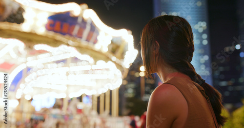 Woman looking at the carousel in the city at night